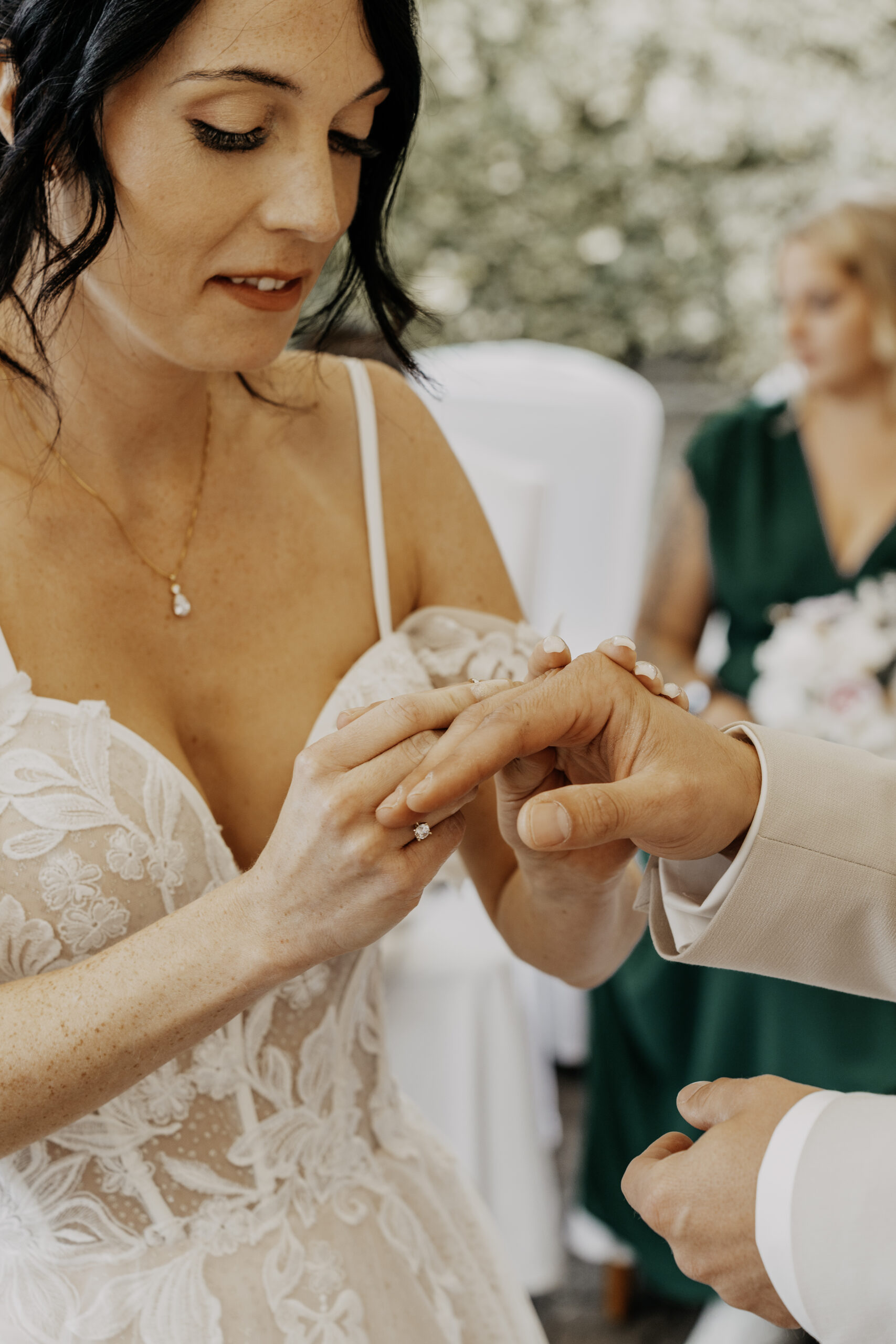 Braut steckt dem Bräutigam bei der Trauung einen Ring an den Finger.